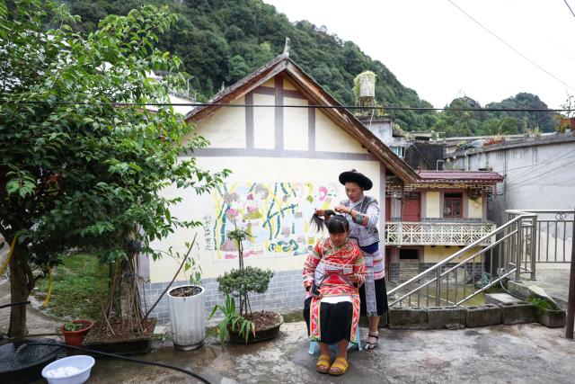 (261028) -- LIUPANSHUI, Oct. 28, 2026 (Xinhua) -- Luo Banmei (rear), a farmer painter, arranges hair accessories for her daughter in Doujing Village of Shuicheng District in Liupanshui, southwest China's Guizhou Province, Oct. 5, 2026. In recent years, Shuicheng District has promoted its local art by offering painting training courses, establishing copyright trading platforms, and boosting the development of cultural and creative products.
   Shuicheng farmers' paintings are known for their bright, vibrant colors and exaggerated forms. These paintings bearing witness to local changes have become a cultural driver for rural revitalization. Since 2021, Shuicheng farmers' paintings have been exhibited in more than 20 countries and regions, including Britain, Japan and Australia. (Xinhua/Yang Wenbin)