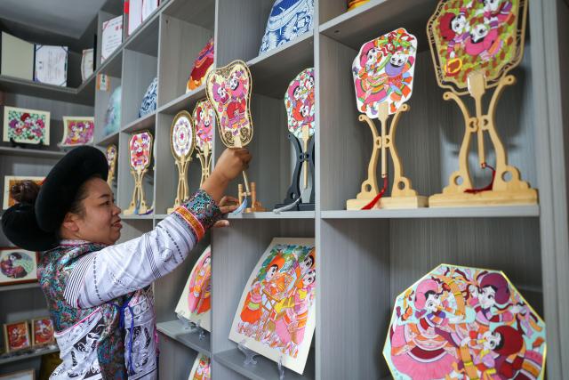 (261028) -- LIUPANSHUI, Oct. 28, 2026 (Xinhua) -- Luo Banmei, a farmer painter, arranges cultural and creative products themed on farmers' paintings in Doujing Village of Shuicheng District in Liupanshui, southwest China's Guizhou Province, Oct. 5, 2026. In recent years, Shuicheng District has promoted its local art by offering painting training courses, establishing copyright trading platforms, and boosting the development of cultural and creative products.
   Shuicheng farmers' paintings are known for their bright, vibrant colors and exaggerated forms. These paintings bearing witness to local changes have become a cultural driver for rural revitalization. Since 2021, Shuicheng farmers' paintings have been exhibited in more than 20 countries and regions, including Britain, Japan and Australia. (Xinhua/Yang Wenbin)