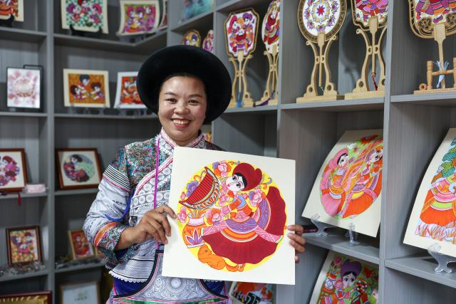 (261028) -- LIUPANSHUI, Oct. 28, 2026 (Xinhua) -- Luo Banmei, a farmer painter, displays a painting in Doujing Village of Shuicheng District in Liupanshui, southwest China's Guizhou Province, Oct. 5, 2026. In recent years, Shuicheng District has promoted its local art by offering painting training courses, establishing copyright trading platforms, and boosting the development of cultural and creative products.
   Shuicheng farmers' paintings are known for their bright, vibrant colors and exaggerated forms. These paintings bearing witness to local changes have become a cultural driver for rural revitalization. Since 2021, Shuicheng farmers' paintings have been exhibited in more than 20 countries and regions, including Britain, Japan and Australia. (Xinhua/Yang Wenbin)