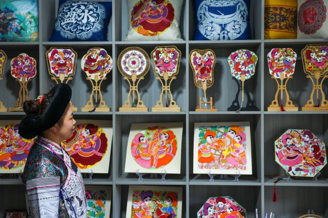 (261028) -- LIUPANSHUI, Oct. 28, 2026 (Xinhua) -- Luo Banmei, a farmer painter, looks at cultural and creative products themed on farmers' paintings in Doujing Village of Shuicheng District in Liupanshui, southwest China's Guizhou Province, Oct. 5, 2026. In recent years, Shuicheng District has promoted its local art by offering painting training courses, establishing copyright trading platforms, and boosting the development of cultural and creative products.
   Shuicheng farmers' paintings are known for their bright, vibrant colors and exaggerated forms. These paintings bearing witness to local changes have become a cultural driver for rural revitalization. Since 2021, Shuicheng farmers' paintings have been exhibited in more than 20 countries and regions, including Britain, Japan and Australia. (Xinhua/Yang Wenbin)