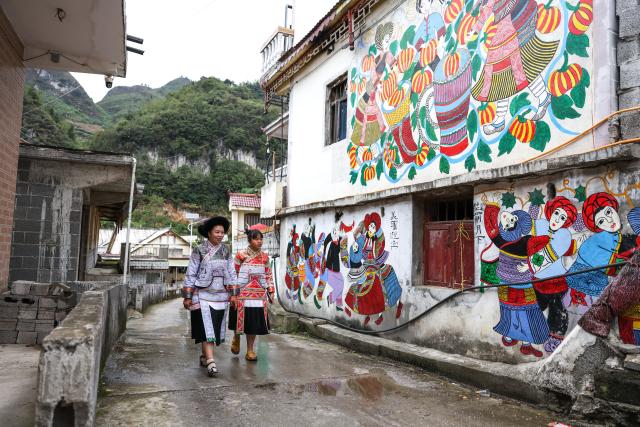 (261028) -- LIUPANSHUI, Oct. 28, 2026 (Xinhua) -- Luo Banmei (L), a farmer painter, walks past farmers' paintings on a wall with her daughter in Doujing Village of Shuicheng District in Liupanshui, southwest China's Guizhou Province, Oct. 5, 2026. In recent years, Shuicheng District has promoted its local art by offering painting training courses, establishing copyright trading platforms, and boosting the development of cultural and creative products.
   Shuicheng farmers' paintings are known for their bright, vibrant colors and exaggerated forms. These paintings bearing witness to local changes have become a cultural driver for rural revitalization. Since 2021, Shuicheng farmers' paintings have been exhibited in more than 20 countries and regions, including Britain, Japan and Australia. (Xinhua/Yang Wenbin)