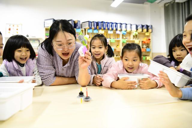 (261028) -- JINAN, Oct. 28, 2026 (Xinhua) -- A teacher guides students to learn about a spinning top launcher at a primary school in Jinan, east China's Shandong Province, Oct. 27, 2026. In recent years, Jinan has strengthened science and technology education in primary and secondary schools. Through a rich array of regular sci-tech themed activities, local schools have deeply integrated scientific knowledge into daily teaching to better nurture students' scientific literacy. (Xinhua/Guo Xulei)