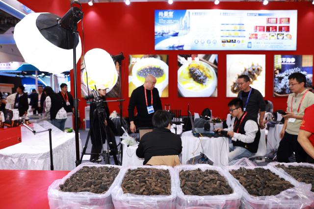 (261028) -- QINGDAO, Oct. 28, 2026 (Xinhua) -- Staff members prepare for a session of live-streaming sale at a booth at the 29th China Fisheries & Seafood Expo in Qingdao, east China's Shandong Province, Oct. 28, 2026. The expo kicked off here on Wednesday, with an exhibition area of approximately 120,000 square meters, showcasing exhibits covering aquatic raw materials and processed products, aquaculture and processing technologies and equipment, and cold chain logistics facilities. The expo, which will last until Oct. 30, has attracted numerous domestic and international manufacturers and buyers to seek business opportunities. (Xinhua/Gao Jing)