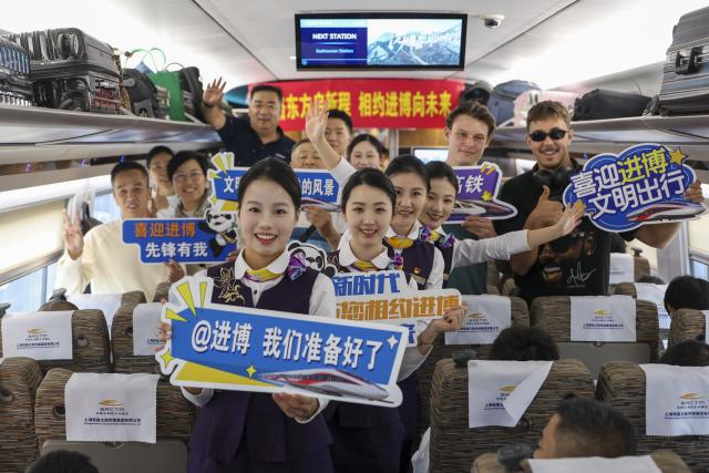(261028) -- SHANGHAI, Oct. 28, 2026 (Xinhua) -- Passengers pose for group photos with staff members during an activity promoting the upcoming 9th China International Import Expo (CIIE) on the train G901, Oct. 28, 2026. A promotion activity was held on the train G901 on Wednesday to show highlights of this year's CIIE, which will be held in Shanghai from Nov. 5 to 10. (Xinhua/Wang Xiang)