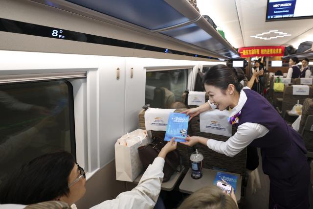(261028) -- SHANGHAI, Oct. 28, 2026 (Xinhua) -- A staff member hands a brochure on China International Import Expo (CIIE) to a passenger during an activity promoting the upcoming 9th CIIE on the train G901, Oct. 28, 2026. A promotion activity was held on the train G901 on Wednesday to show highlights of this year's CIIE, which will be held in Shanghai from Nov. 5 to 10. (Xinhua/Wang Xiang)