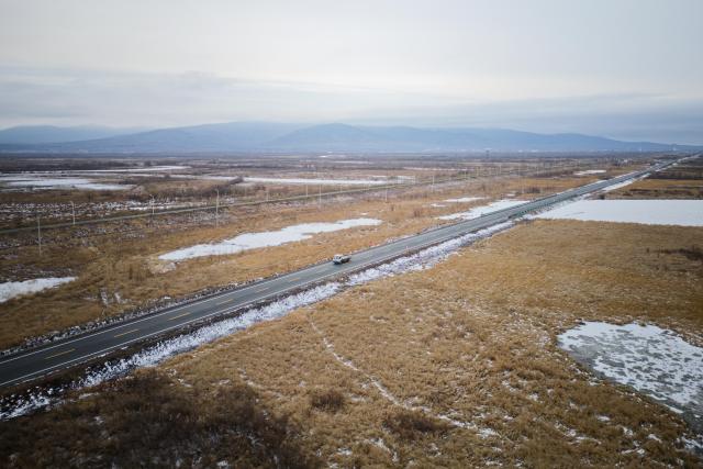 (261030) -- FUYUAN, Oct. 30, 2026 (Xinhua) -- An aerial drone photo shows a vehicle going on a trial driving on the road leading to the Heixiazi Island Road Port, Oct. 30, 2026. A completion ceremony for the construction of the Heixiazi Island Road Passenger Port was held in Fuyuan City on Friday. 
  The Heixiazi Island Road Port will provide efficient round-the-clock customs clearance, effectively easing the clearance pressure on the Fuyuan Port, and deepening economic and trade cooperation and cultural exchanges between China and Russia. (Xinhua/Zhang Tao)