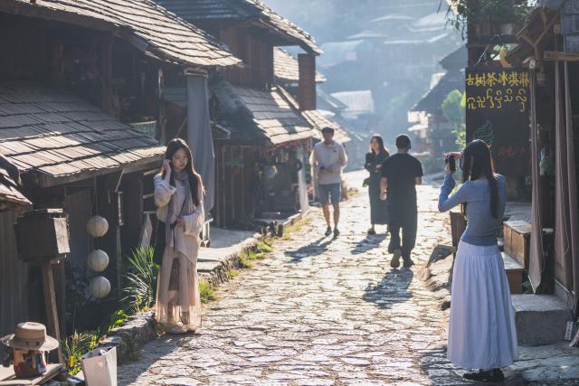 (261030) -- PU'ER, Oct. 30, 2026 (Xinhua) -- A tourist poses for photos in Nuogan Village of Lancang Lahu Autonomous County of Pu'er City, southwest China's Yunnan Province, Oct. 30, 2026. (Xinhua/Wang Guansen)
