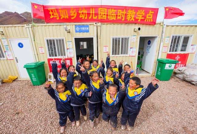 (261030) -- BAQEN, Oct. 30, 2026 (Xinhua) -- Children pose for photos in front of a makeshift kindergarten at a resettlement site of a quake-hit village in Maru Township of Baqen County, Nagqu City, southwest China's Xizang Autonomous Region, on Oct. 30, 2026. A makeshift kindergarten opened recently at a resettlement site here. Inside the comprehensively disinfected and carefully decorated facility, teachers are helping children from quake-hit villages adapt as soon as possible to learning and daily life at the resettlement site. (Xinhua/Tenzin Nyida)