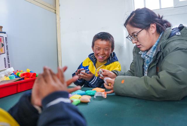 (261030) -- BAQEN, Oct. 30, 2026 (Xinhua) -- Children make handicrafts under the guidance of a teacher at a makeshift kindergarten at a resettlement site of a quake-hit village in Maru Township of Baqen County, Nagqu City, southwest China's Xizang Autonomous Region, on Oct. 30, 2026. A makeshift kindergarten opened recently at a resettlement site here. Inside the comprehensively disinfected and carefully decorated facility, teachers are helping children from quake-hit villages adapt as soon as possible to learning and daily life at the resettlement site. (Xinhua/Tenzin Nyida)
