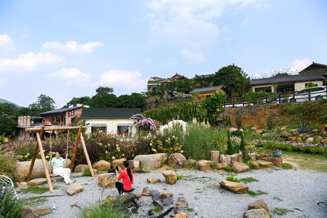 (261030) -- XINGYE, Oct. 30, 2026 (Xinhua) -- A tourist poses for photos in Kuishan Village of Xingye County, Yulin City, south China's Guangxi Zhuang Autonomous Region, Oct. 30, 2026. Since the beginning of this year, Xingye County has been implementing a "six improvements" program in villages, focusing on the practical improvements in manufacturing, agricultural industry, green space, road access, water facilities, and streetlights. These measures are creating fresh momentum for rural revitalization. (Xinhua/Cao Yiming)