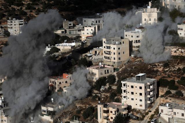 (261030) -- HEBRON, Oct. 30, 2026 (Xinhua) -- Smoke rises after Israeli forces blew up the homes of two Palestinians accused of killing two Israeli soldiers in the southern West Bank city of Hebron, Oct. 30, 2026. Israeli forces on Friday blew up the homes of two Palestinians accused of killing two Israeli soldiers in the southern West Bank city of Hebron, as a military operation entered its eighth day and displaced hundreds of families. (Photo by Mamoun Wazwaz/Xinhua)