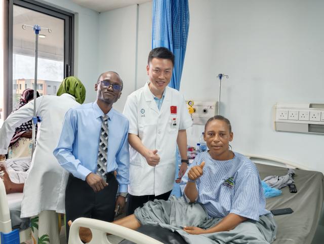 (261030) -- DAR ES SALAAM, Oct. 30, 2026 (Xinhua) -- Wang Wei (C), a urological specialist of the 36th Chinese medical team in Zanzibar, poses for a photo with a local doctor and patient after the successful minimally invasive ureteral reconstruction surgery at Lumumba Hospital in Zanzibar, Tanzania, Oct. 27, 2026. TO GO WITH "Feature: Tanzania's Zanzibar mother finds new hope after life-changing surgery by Chinese doctors" (The 36th Chinese medical team in Zanzibar/Handout via Xinhua)