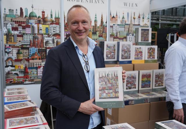 (261031) -- COPENHAGEN, Oct. 31, 2026 (Xinhua) -- An exhibitor displays a jigsaw puzzle featuring his illustration of Copenhagen's buildings at Bogforum in Copenhagen, Denmark, Oct. 30, 2026. Bogforum, Denmark's largest literary festival, opened at Copenhagen's Bella Center on Friday, bringing together authors, publishers and readers for three days of book displays, talks and cultural activities. (Photo by Liu Zhichao/Xinhua)