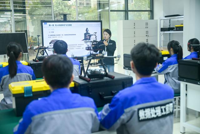 (261031) -- QINGZHEN, Oct. 31, 2026 (Xinhua) -- A teacher briefs students on knowledge of drone application technology at Guizhou Communication Polytechnic University in Qingzhen vocational education town, Qingzhen City, southwest China's Guizhou Province, Oct. 30, 2026. Recently, the mountainous southwestern Chinese province of Guizhou has officially launched its first campus low-altitude drone delivery route in Qingzhen vocational education town. The aerial route connects local commercial districts directly to campuses, cutting the delivery time for teachers and students to less than 20 minutes with delivery fees starting at 3.8 yuan (about 0.57 U.S. dollars). The service also helps build a training platform integrating low-altitude industry and education to support talent cultivation. (Photo by Yuan Fuhong/Xinhua)