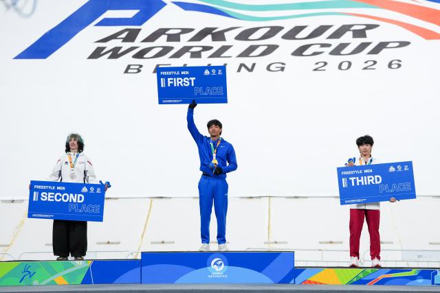 (261031) -- BEIJING, Oct. 31, 2026 (Xinhua) -- Gold medalist Ryan Abiang (C) of the United States, silver medalist Eloan Hitz (L) of France and bronze medalist Fu Kaige of China pose for photos during the awarding ceremony of the men's freestyle competition at the Parkour World Cup Beijing 2026 at Shougang Park in Beijing, capital of China, Oct. 31, 2026. (Xinhua/Ju Huanzong)