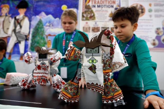 (261031) -- BUCHAREST, Oct. 31, 2026 (Xinhua) -- Participants of a school team present dancing robots dressed in traditional Romanian costumes during the 5th edition of Robofest, a technology event, at the Polytechnic University in Bucharest, Romania, Oct. 31, 2026. The three-day festival dedicated to science, technology and robots includes, among other events, a Robochallenge contest. (Photo by Cristian Cristel/Xinhua)